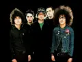 Cinq musiciens, dont certains avec des coiffures afro, posent pour une photo de groupe. L'un porte une casquette "Los Angeles". Ils sont prêts pour une soirée **at the drive in**.