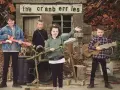 Quatre enfants jouent de la musique devant un panneau "the cranberries". L'un tient une guitare rose, un autre une guitare en bois.