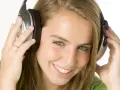 Jeune femme souriante avec des écouteurs, profitant de sa musique à 110 décibels.