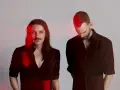 Les membres de Placebo, Brian Molko et Stefan Olsdal, posent en noir et blanc avec des éclats de lumière rouge.