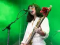 La chanteuse des Pixies, Kim Deal, joue de la basse sur scène, éclairée par une lumière verte.