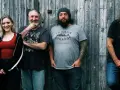 Le groupe de Robert Plant, avec ses musiciens, pose devant un mur de bois.