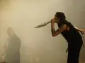 Marilyn Manson chante dans un micro en forme de couteau, un autre musicien est flou à gauche. L'ambiance d'un concert de Marilyn Manson album.