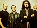 Les membres de System of a Down posent ensemble, chacun avec un style distinct.