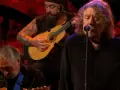 Robert Plant, le légendaire chanteur de Led Zeppelin, en pleine performance, accompagné de musiciens jouant de la guitare.