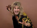 Ozzy Osbourne, le prince des ténèbres, avec sa chevelure blonde ébouriffée et un regard intense, porte une veste noire ornée de motifs dorés.