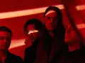 Les membres de Bad Omens posent dans une ambiance rouge intense, éclairés par des ombres dramatiques.