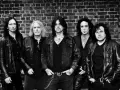 Les membres de Black Star Riders posent devant un mur de briques.