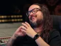Jonathan Davis, le chanteur de Korn, rit en studio d'enregistrement, lunettes sur le nez et longue chevelure brune.