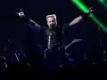 James Hetfield, un des membres de Metallica, salue la foule avec les cornes du diable, éclairé par des faisceaux verts.
