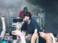 La chanteuse de Crystal Castles, Alice Glass, chante devant une foule. Un autre membre est derrière elle.