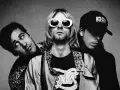 Les membres de Nirvana posent ensemble, Kurt Cobain au centre avec ses lunettes blanches iconiques.