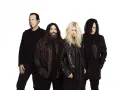 Les membres de The Pretty Reckless, un groupe de rock, posent ensemble sur fond blanc.