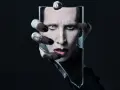 Marilyn Manson, visage décomposé dans un miroir brisé, évoquant l'esthétique sombre de ses albums.