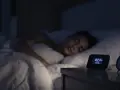 Une jeune femme dort paisiblement. Sur la table de nuit, un réveil affiche 10:20. La question est : combien de décibels pour dormir ?