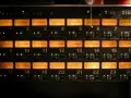 Rack d'équipements audio avec 24 vu-mètres orange illuminés, indiquant des niveaux sonores pouvant atteindre 76 décibels équivalents.