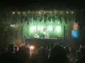 Une dj femme française enflamme la foule sous une décoration jungle. Lumières vertes, fumée et boule à facettes créent une ambiance festive.