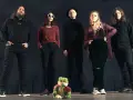 Cinq personnes se tiennent devant un fond sombre. Au premier plan, une grenouille en peluche tient une rose. Le groupe, comme un **crippled black phoenix**, semble prêt à s'envoler.