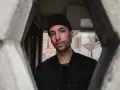 Tim Hecker, artiste sonore, regarde à travers une structure architecturale.