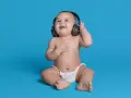 Un bébé souriant, en couche, écoute de la musique avec des écouteurs, le décibel maximum pour un bébé est à éviter.
