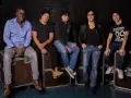 Les membres de Trust (groupe) posent ensemble, assis sur des flight cases, prêts pour leur prochaine performance.