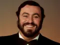 Portrait souriant de Luciano Pavarotti, le célèbre chanteur rock italien, en costume noir et nœud papillon.