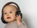 Un bébé curieux avec un casque anti-bruit. Quand utiliser un casque anti-bruit bébé à partir de quel âge ?