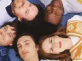 Les membres de Metronomy, cinq visages souriants, forment une étoile sur un fond bleu.