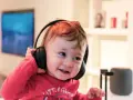 Un enfant qui ne supporte pas le bruit trouve le calme avec ses écouteurs, un sourire aux lèvres.