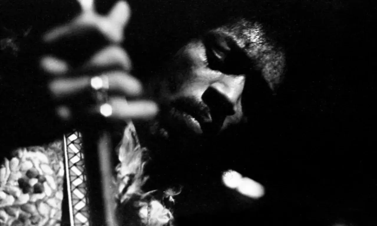 Gros plan en noir et blanc de Jimi Hendrix jouant de la guitare, évoquant l'esprit de ses albums légendaires.