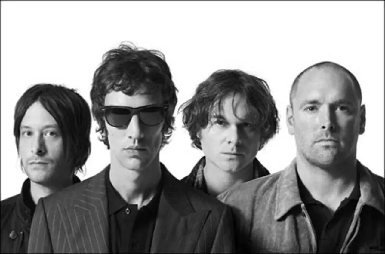 Quatre hommes, membres du groupe The Verve, posent ensemble. Leurs regards sont intenses, capturant l'énergie du groupe.