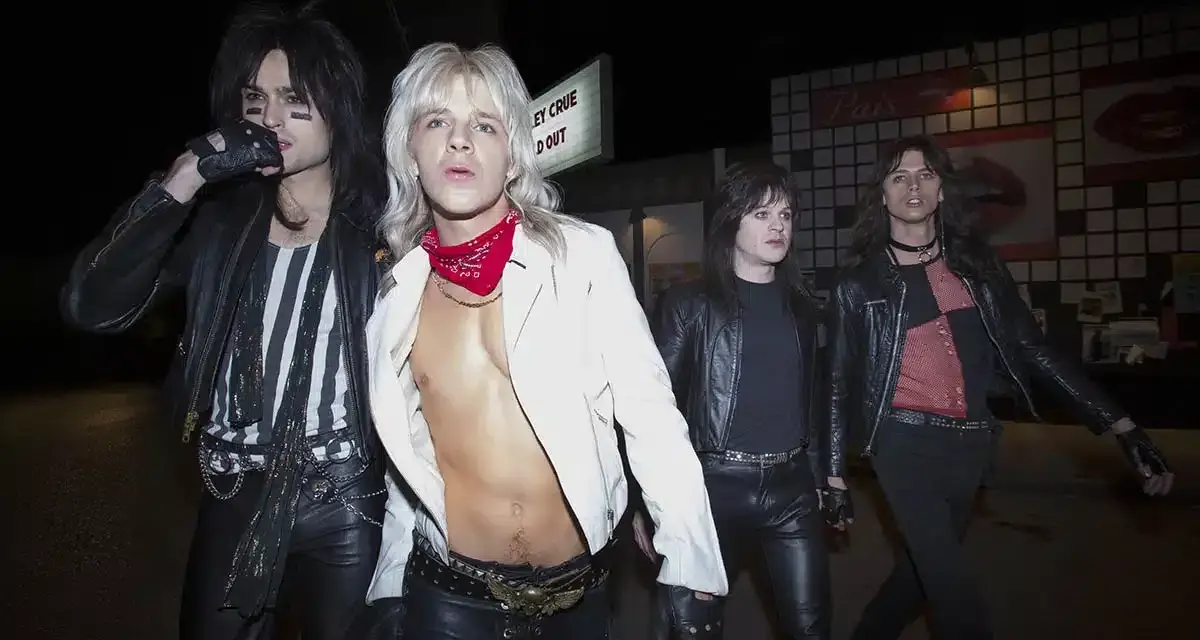 Quatre membres du groupe Motley Crue, vêtus de cuir noir et de maquillage, marchent dans la nuit.