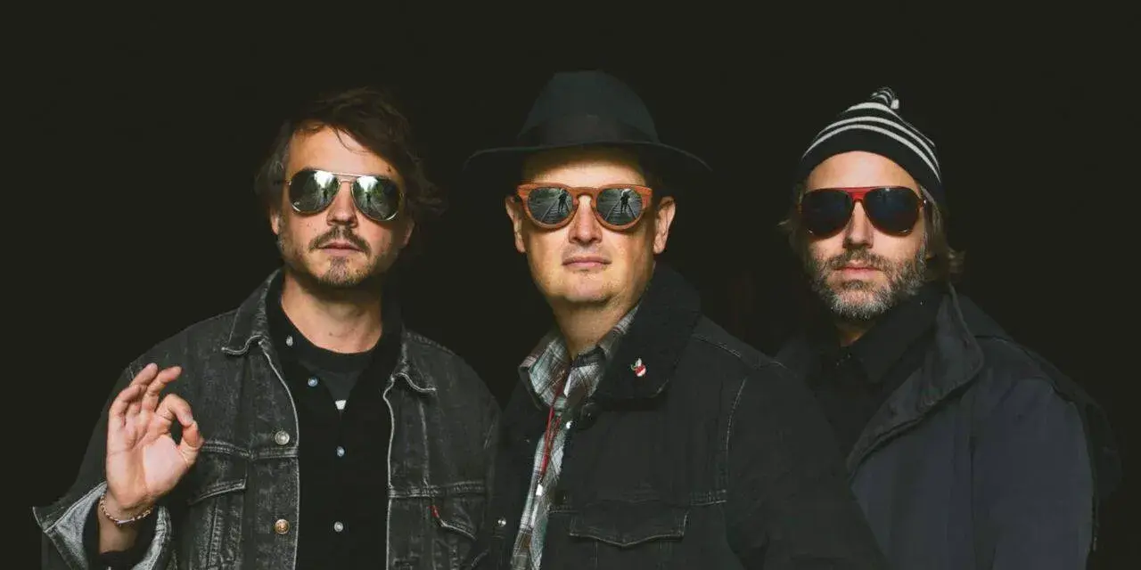 Trois hommes, lunettes de soleil, chapeau, bonnet. Ils ont l'air cool, pas comme des zombies.