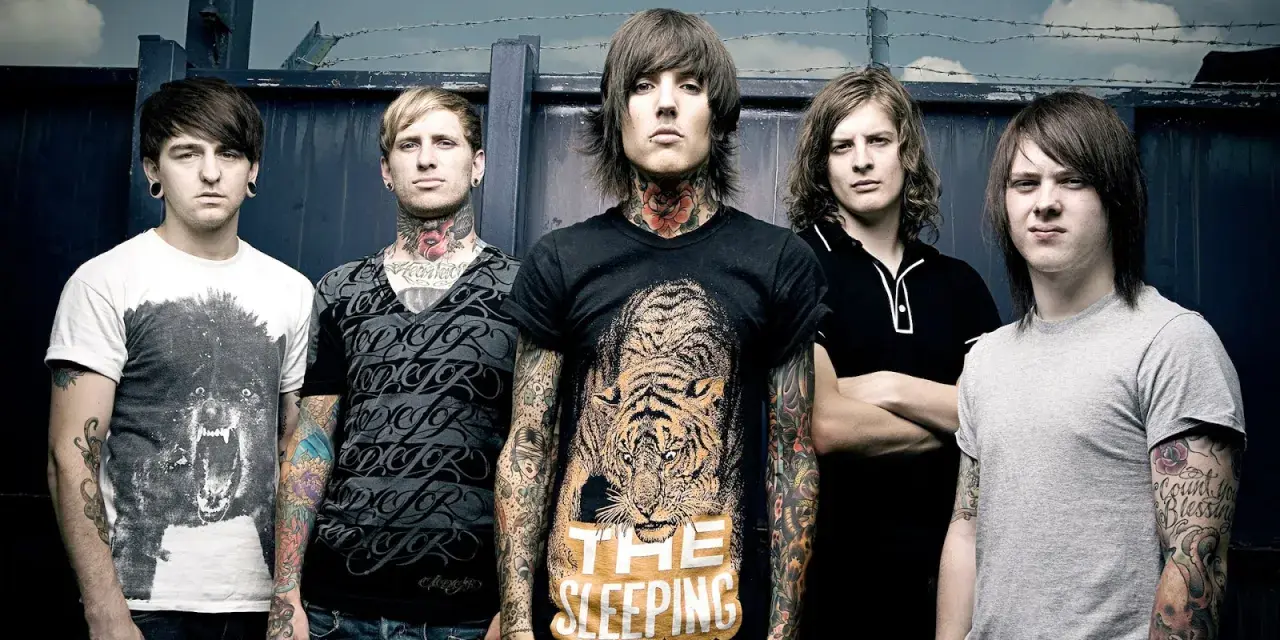 Cinq membres du groupe Bring Me The Horizon posent devant une clôture. Le chanteur porte un t-shirt avec un tigre et le texte "The Sleeping".