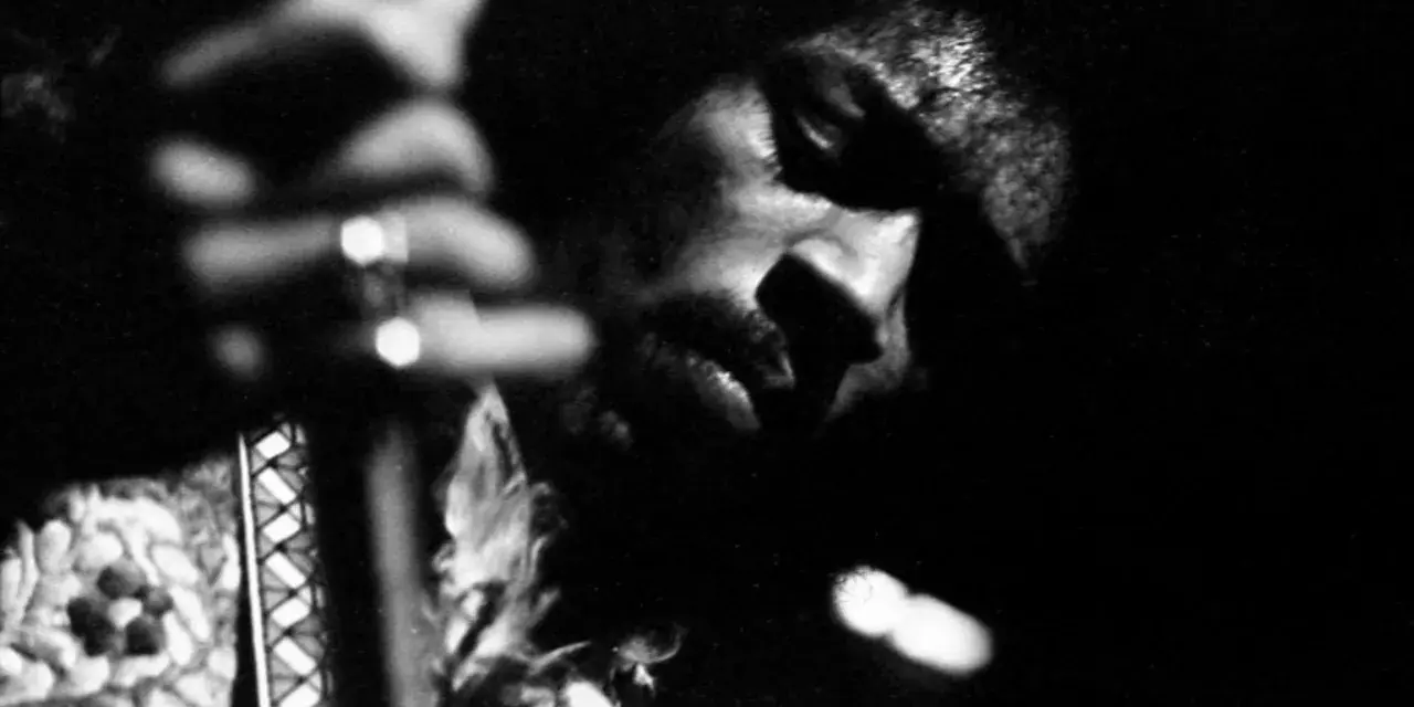Gros plan en noir et blanc de Jimi Hendrix jouant de la guitare, évoquant l'esprit de ses albums légendaires.