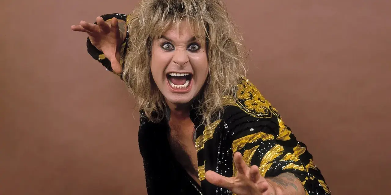 Ozzy Osbourne, le prince des ténèbres, avec sa chevelure blonde ébouriffée et un regard intense, porte une veste noire ornée de motifs dorés.