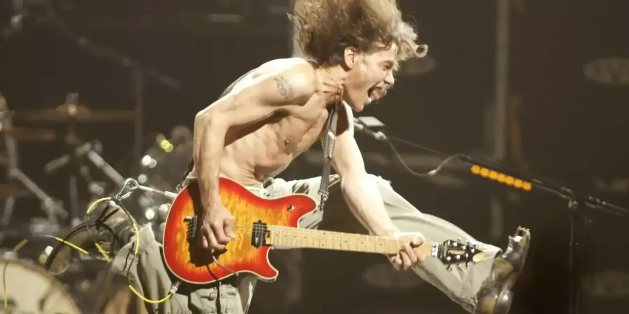 Un guitariste en plein saut, cheveux au vent, déchaîne sa guitare. Un vrai héros de la guitare en pleine action.