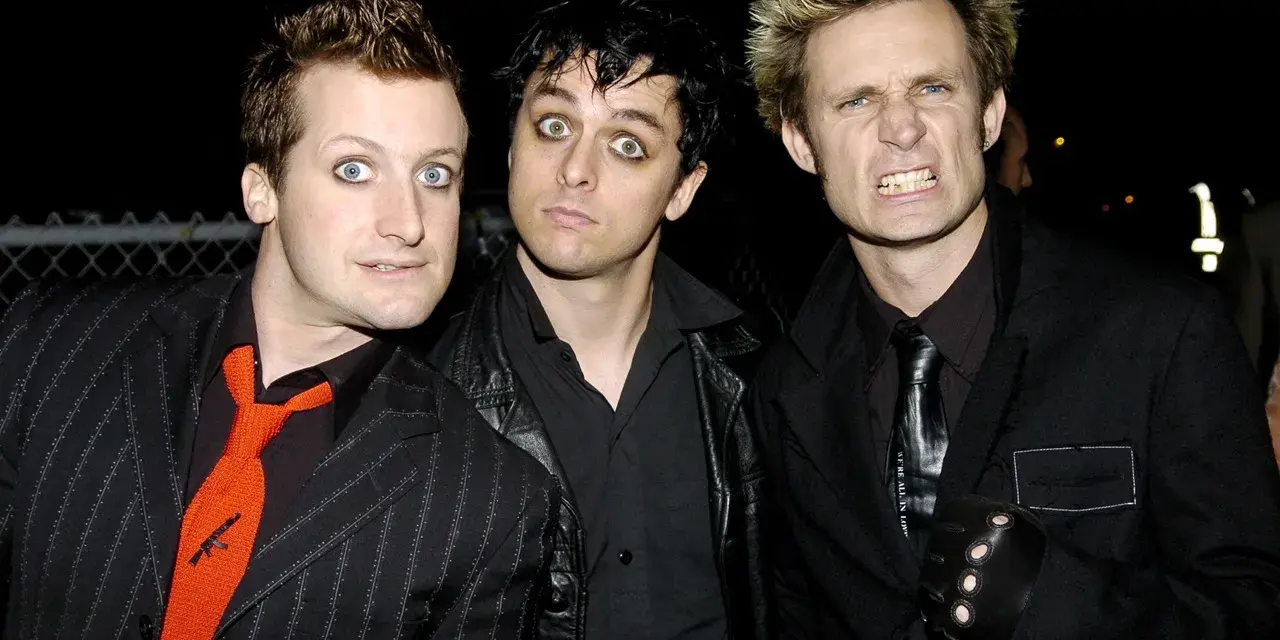 Les membres de Green Day, Billie Joe Armstrong, Mike Dirnt et Tré Cool, posent ensemble. Armstrong a les yeux écarquillés, Dirnt a un regard intense et Cool fait une grimace.