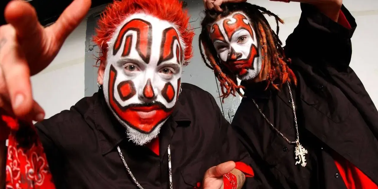 Deux membres du groupe Insane Clown Posse, visage peint en clown, cheveux rouges et dreadlocks, portent des chemises noires et des bandanas rouges.