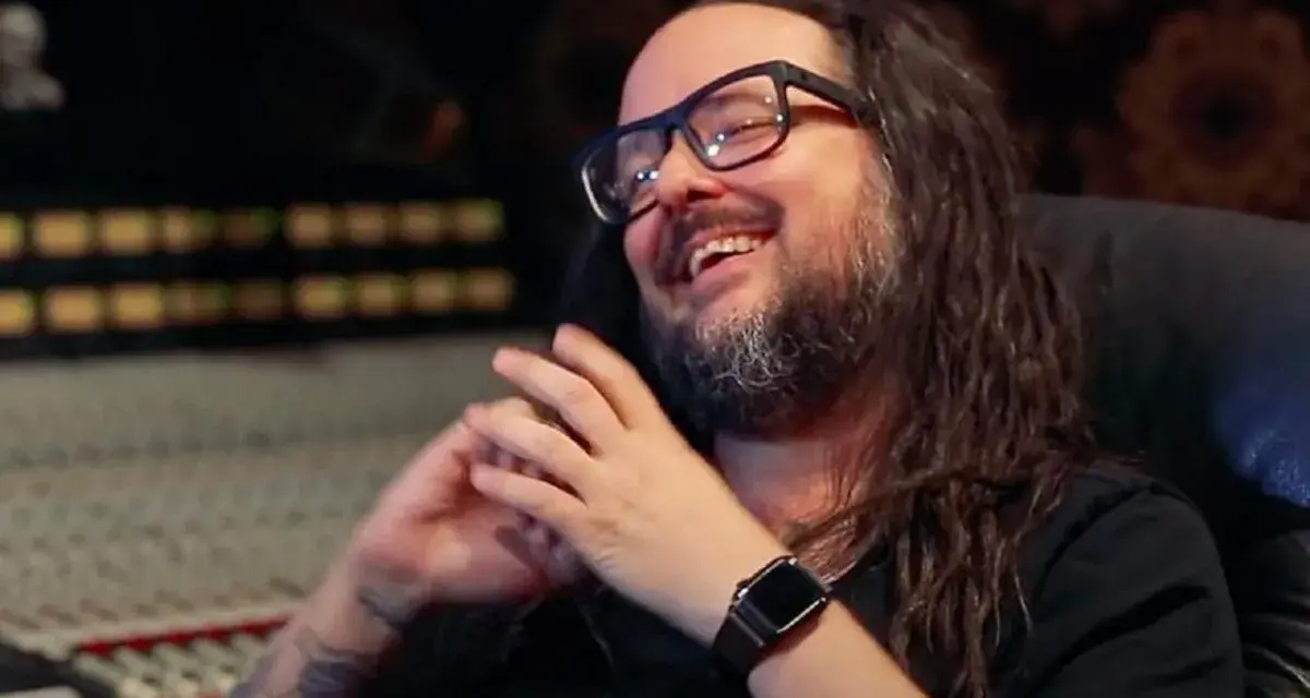 Jonathan Davis, le chanteur de Korn, rit en studio d'enregistrement, lunettes sur le nez et longue chevelure brune.