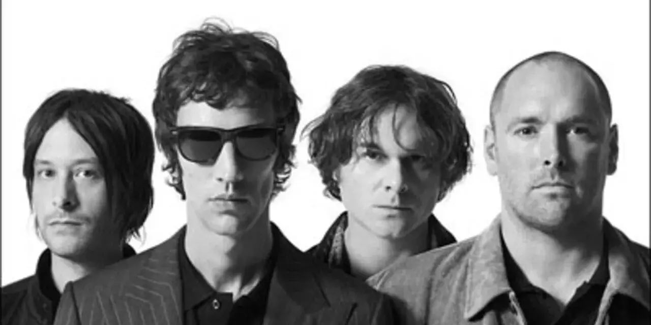 Quatre hommes, membres du groupe The Verve, posent ensemble. Leurs regards sont intenses, capturant l'énergie du groupe.