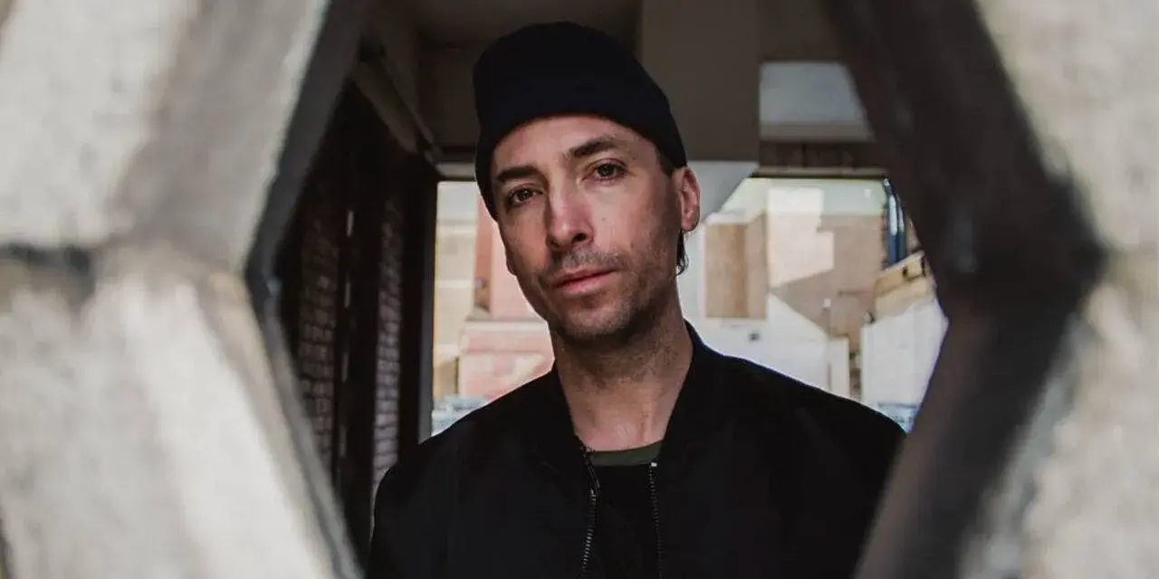 Tim Hecker, artiste sonore, regarde à travers une structure architecturale.