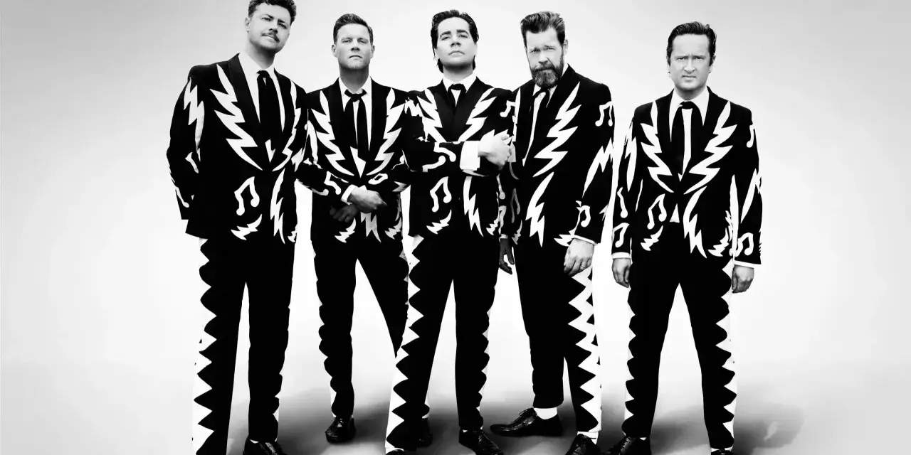 Les membres de The Hives posent en costumes noirs et blancs à motifs d'éclairs et de notes de musique.
