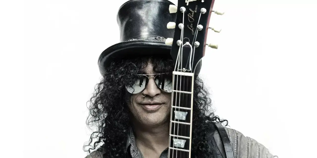 Le guitariste Slash, avec son chapeau haut-de-forme et ses lunettes de soleil, pose avec sa guitare Gibson Les Paul.
