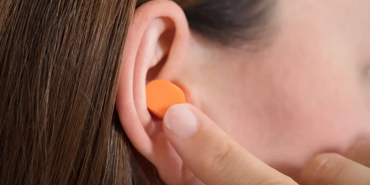 Une personne insère une boule quies en mousse orange dans son oreille. Peut on laver des boules quies en mousse ?