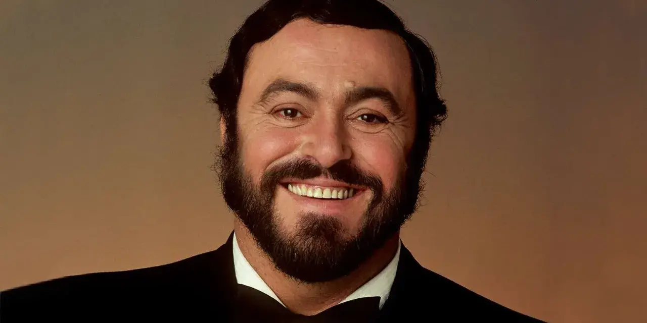 Portrait souriant de Luciano Pavarotti, le célèbre chanteur rock italien, en costume noir et nœud papillon.