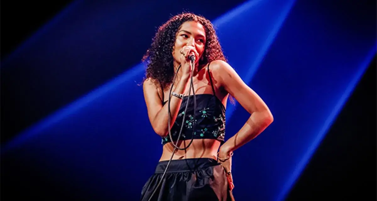 La chanteuse soul française, avec sa voix envoûtante, captive le public sous les projecteurs bleus.