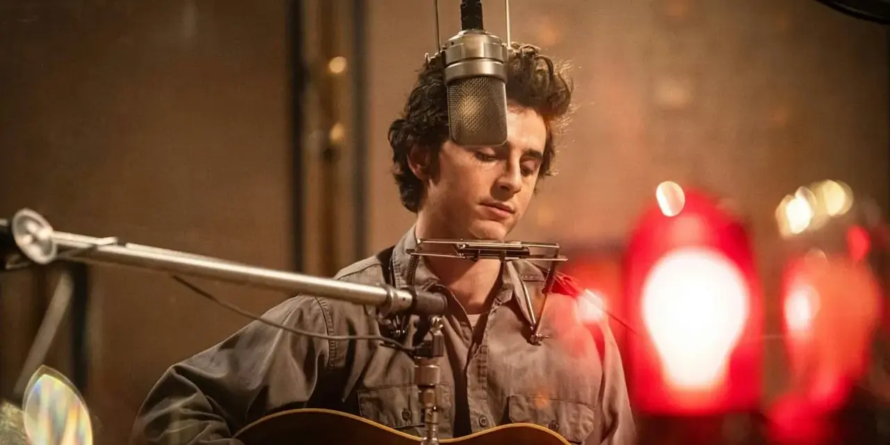 Un jeune homme à la guitare et à l'harmonica, dans un style de musique rappelant Bob Dylan, enregistre en studio.