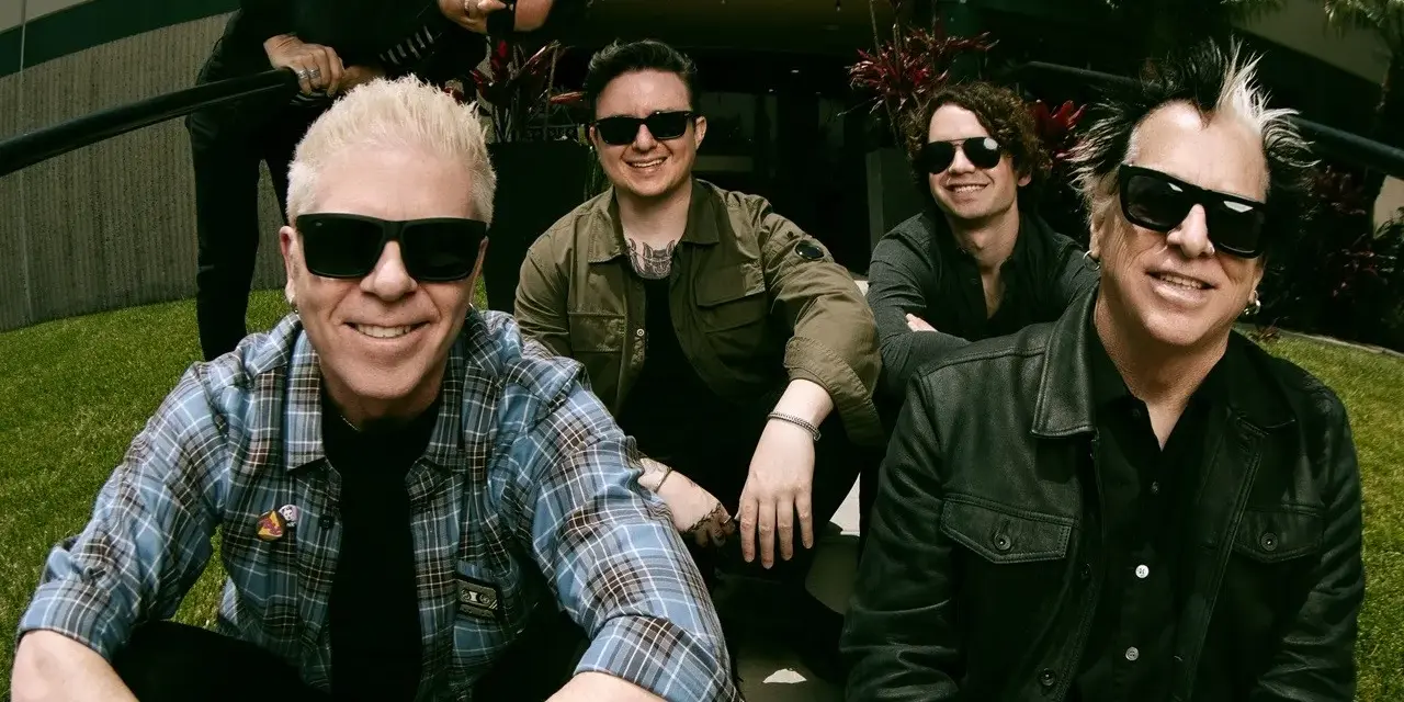 Les membres de The Offspring posent ensemble, souriants et portant des lunettes de soleil. Le groupe semble prêt pour une nouvelle aventure musicale.