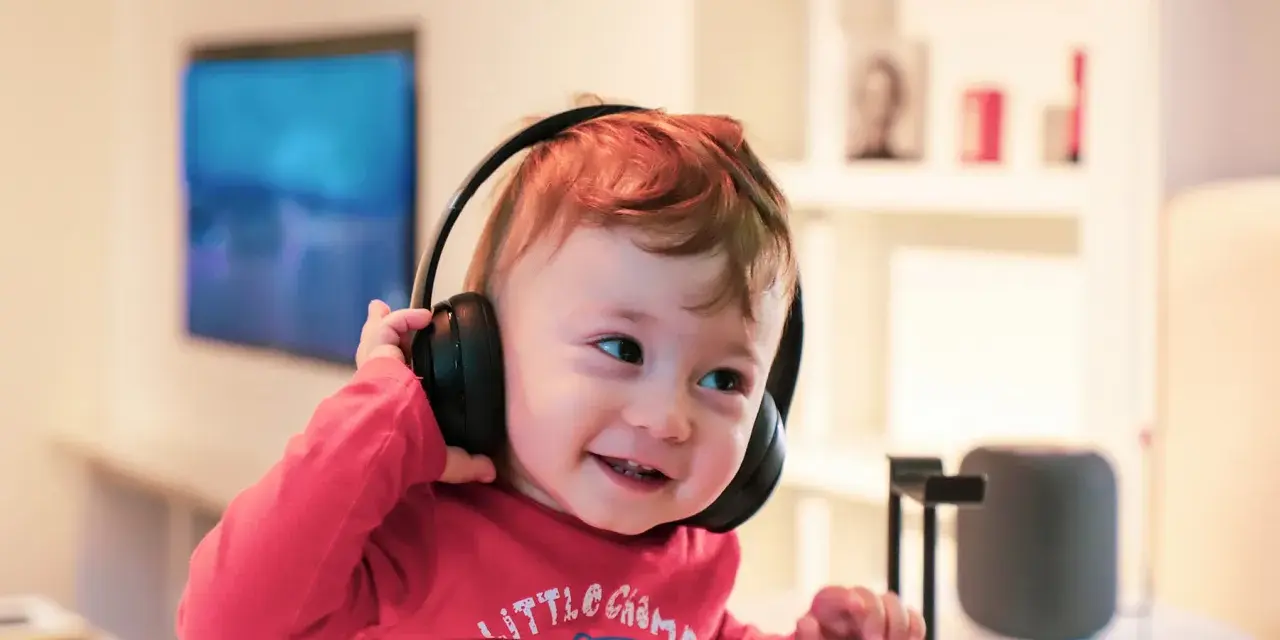 Un enfant qui ne supporte pas le bruit trouve le calme avec ses écouteurs, un sourire aux lèvres.